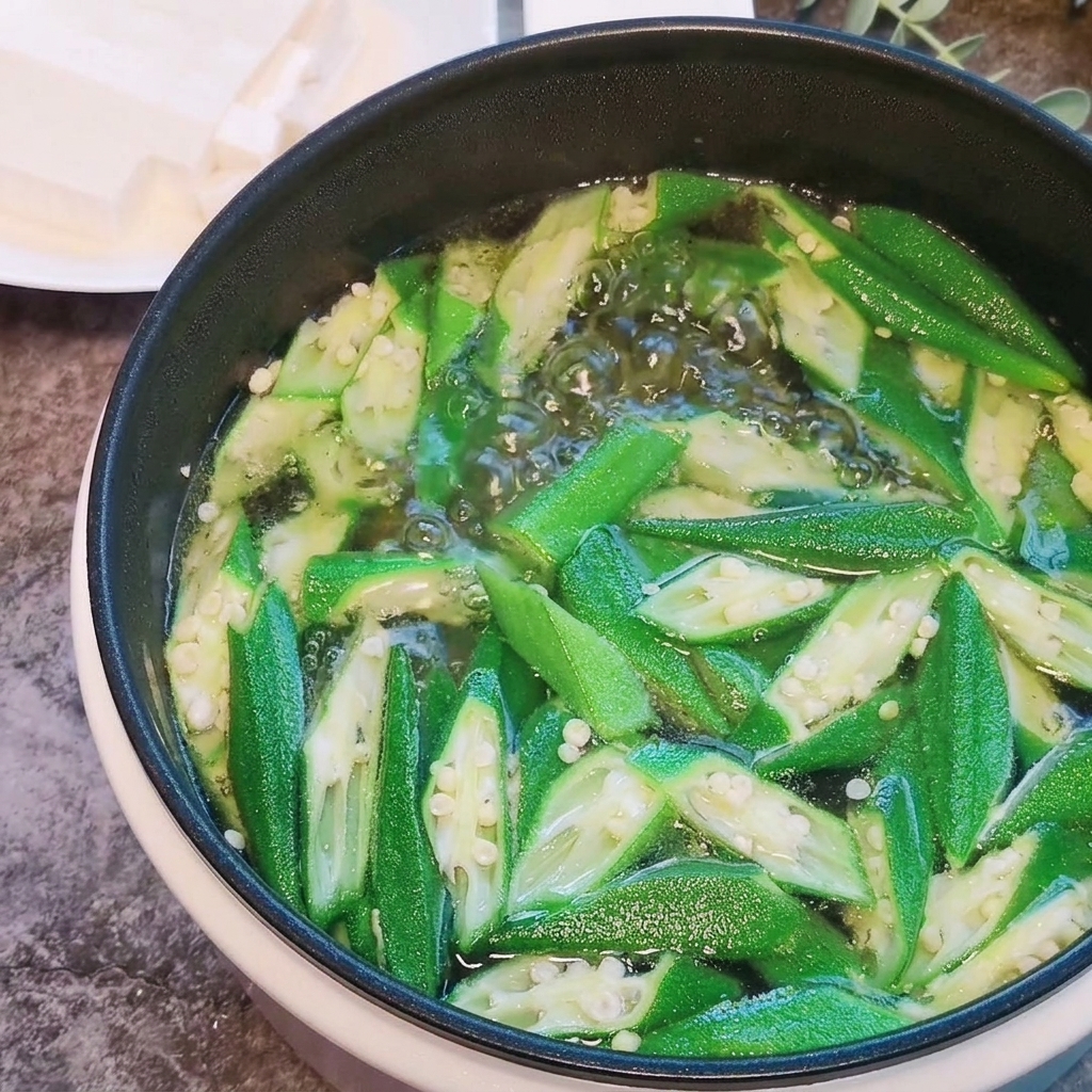 끓는 오크라 국물에 연두부 큐브를 조심스럽게 넣는 모습.