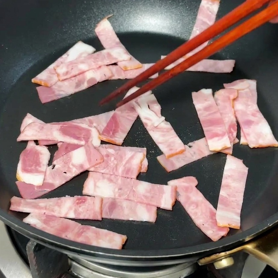 팬에서 베이컨이 노릇하게 익으며 기름이 나오는 모습.