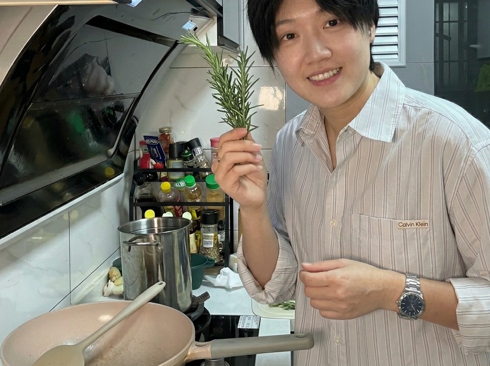 뜨거운 팬 속 베이컨 기름에 신선한 녹색 타임 가지를 넣어 향을 내는 모습.