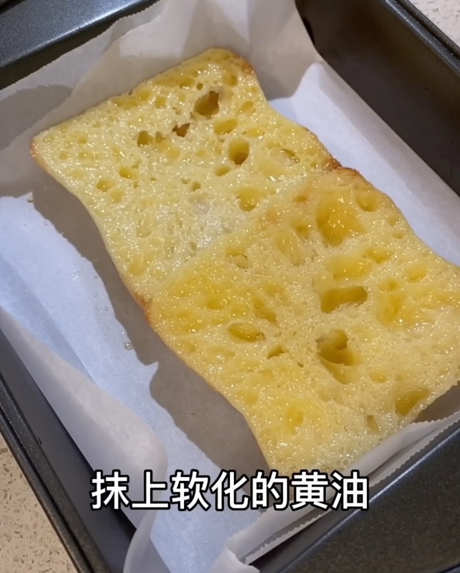 마늘을 문지른 치아바타 조각 표면에 부드러운 버터를 바르는 모습.