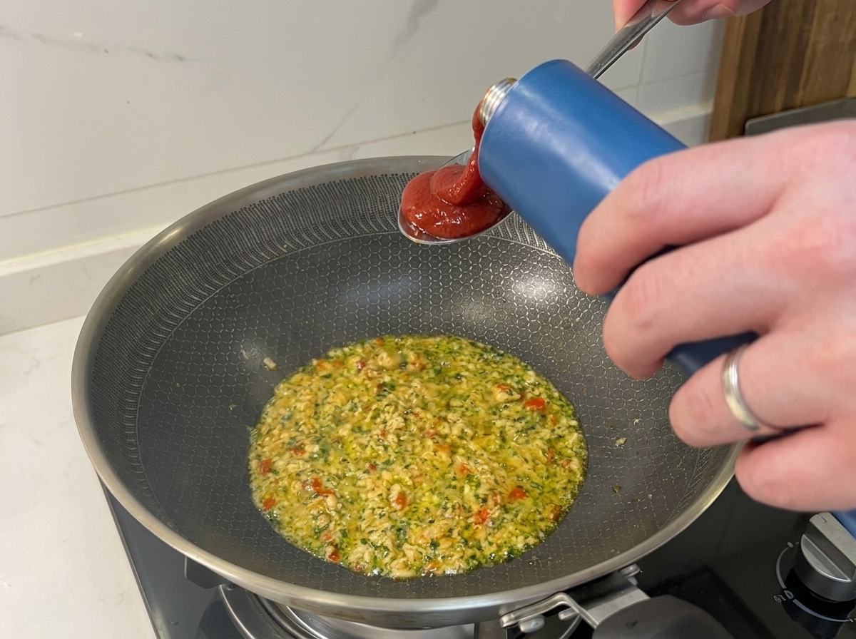 참치와 재료들이 볶아진 팬에 토마토 파사타를 붓는 모습.