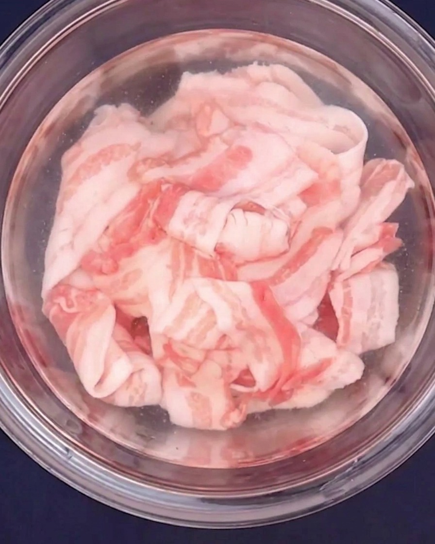 얇게 썬 돼지고기를 유리 볼에 담고 뜨거운 물로 데치는 모습.