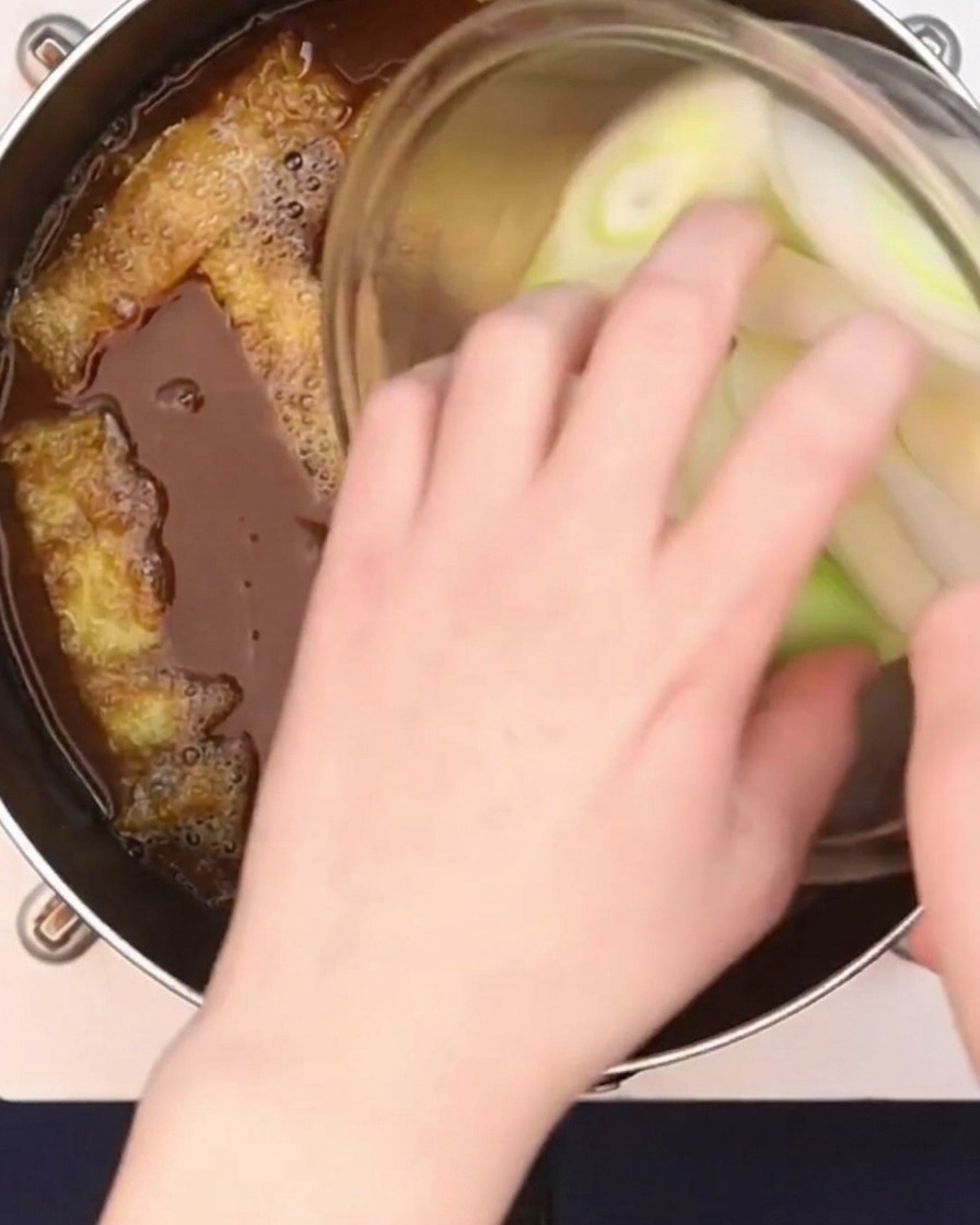 어슷 썬 대파를 끓는 카레 국물에 넣는 모습.