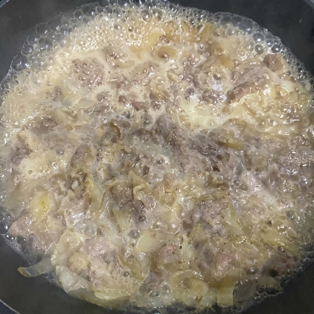 주걱으로 끓고 있는 소고기 덮밥 육수의 거품을 걷어내는 모습.