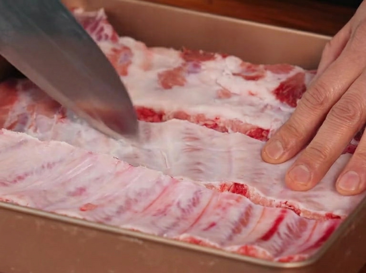 칼을 사용하여 등갈비 뒷면의 근막에 칼집을 내는 모습.