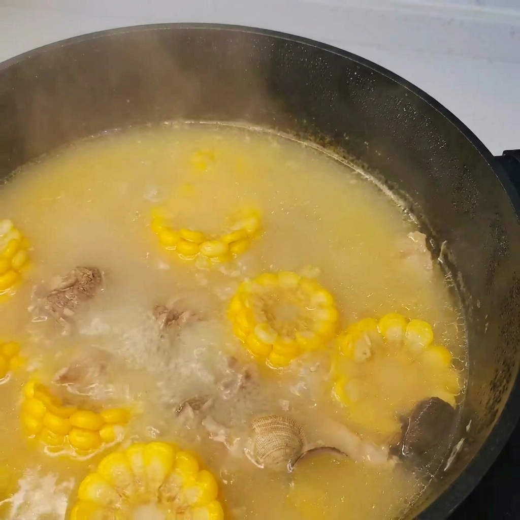 돼지갈비, 바지락, 채소가 끓는 냄비에 다시마를 넣는 모습.