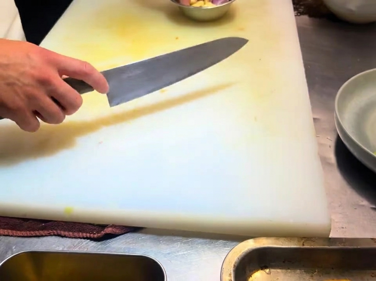 흰 도마 위에 얇게 썬 마늘 슬라이스가 펼쳐져 있습니다.