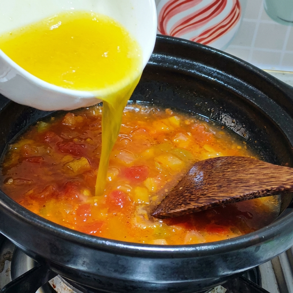 볶은 토마토가 든 냄비에 닭 육수를 붓는 모습.