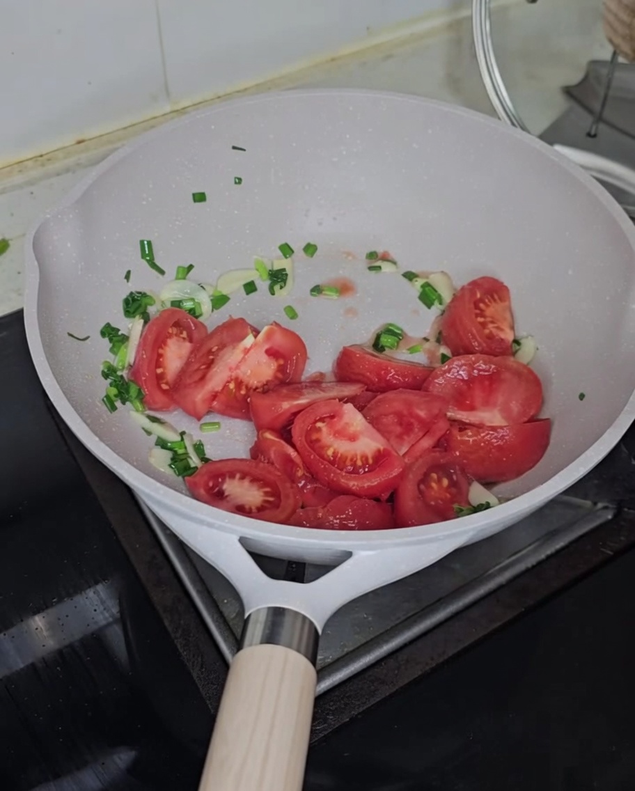 볶은 채소에 토마토를 넣고 함께 볶는 모습.