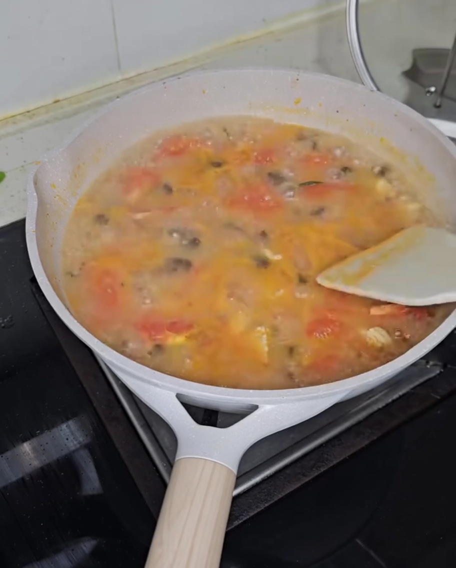 그릇에 담긴 완성된 토마토 닭고기 수제비 위에 파를 뿌리는 모습.