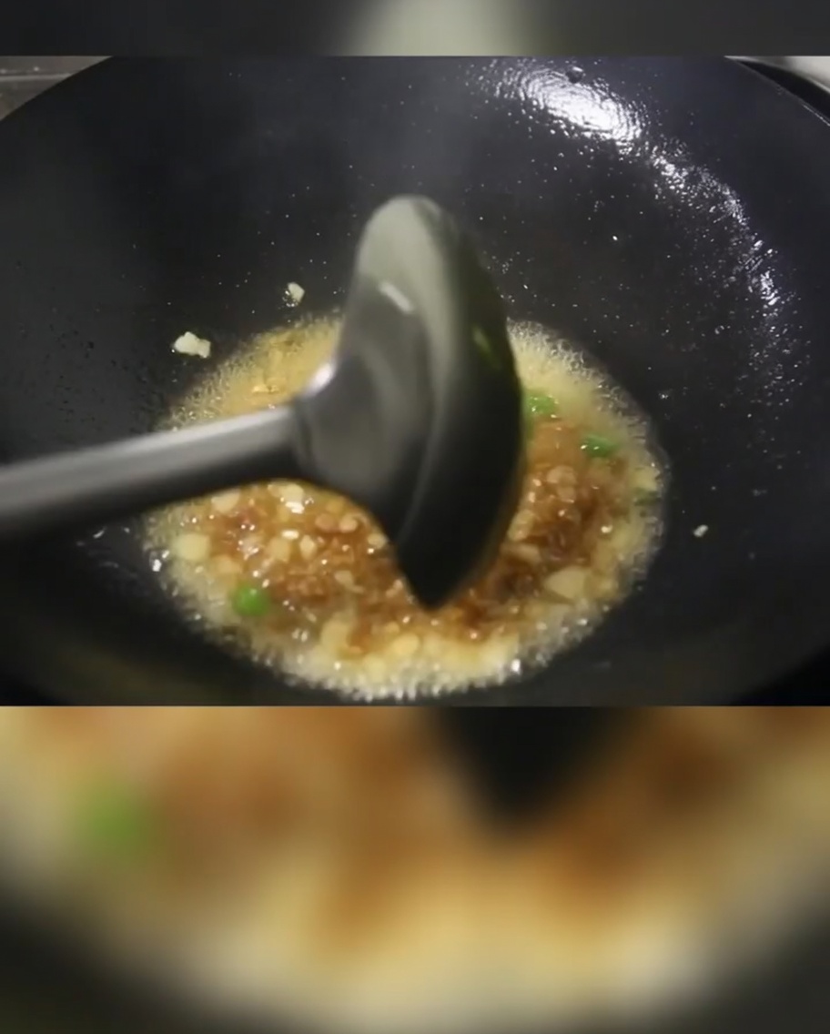 웍에서 대파, 돼지고기, 감자 큐브가 식용유에 볶아지고 있는 모습.