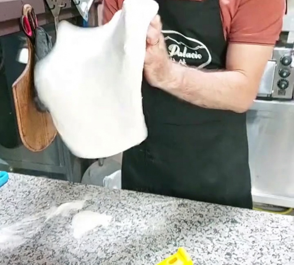 피자 도우를 공중에서 돌리며 모양을 잡는 모습.