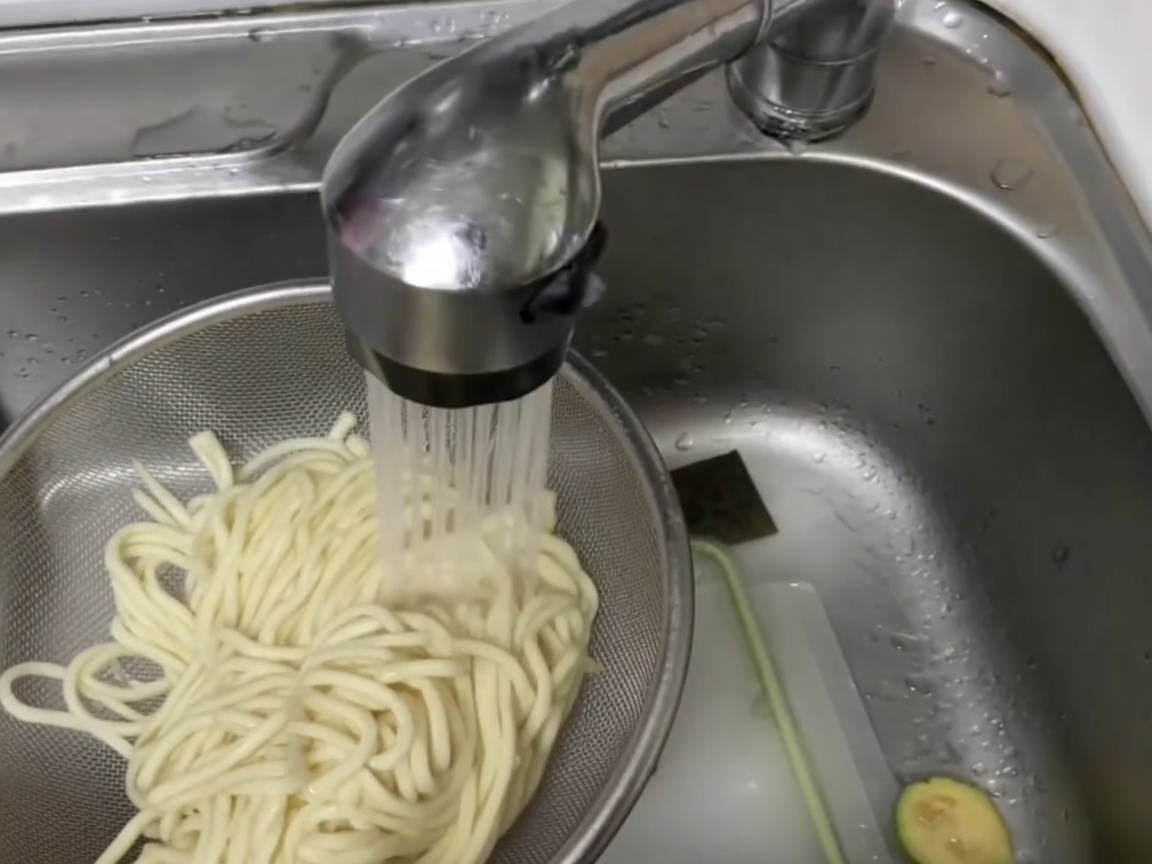 체에 밭친 칼국수 면을 찬물에 살짝 헹구는 모습.