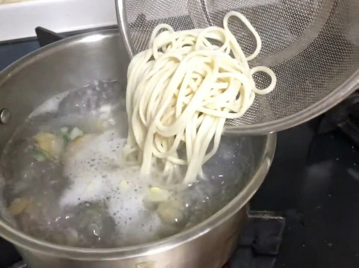 끓는 육수에 헹군 면을 조심스럽게 넣는 모습.