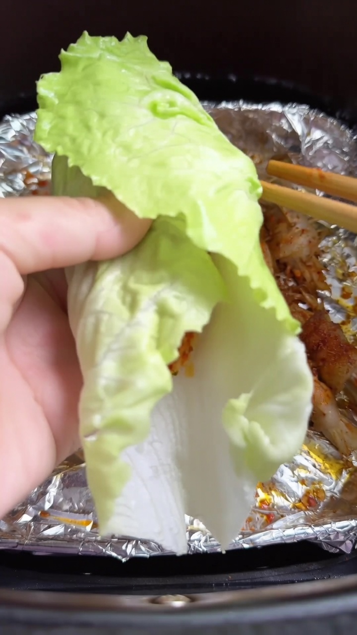 신선한 상추 위에 올려진 바삭한 에어프라이어 삼겹살 팽이버섯 말이의 근접 모습.