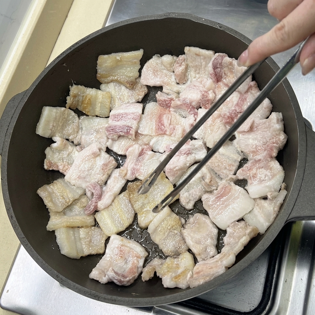 팬에서 노릇노릇하게 구워지며 기름이 빠져나오는 삼겹살