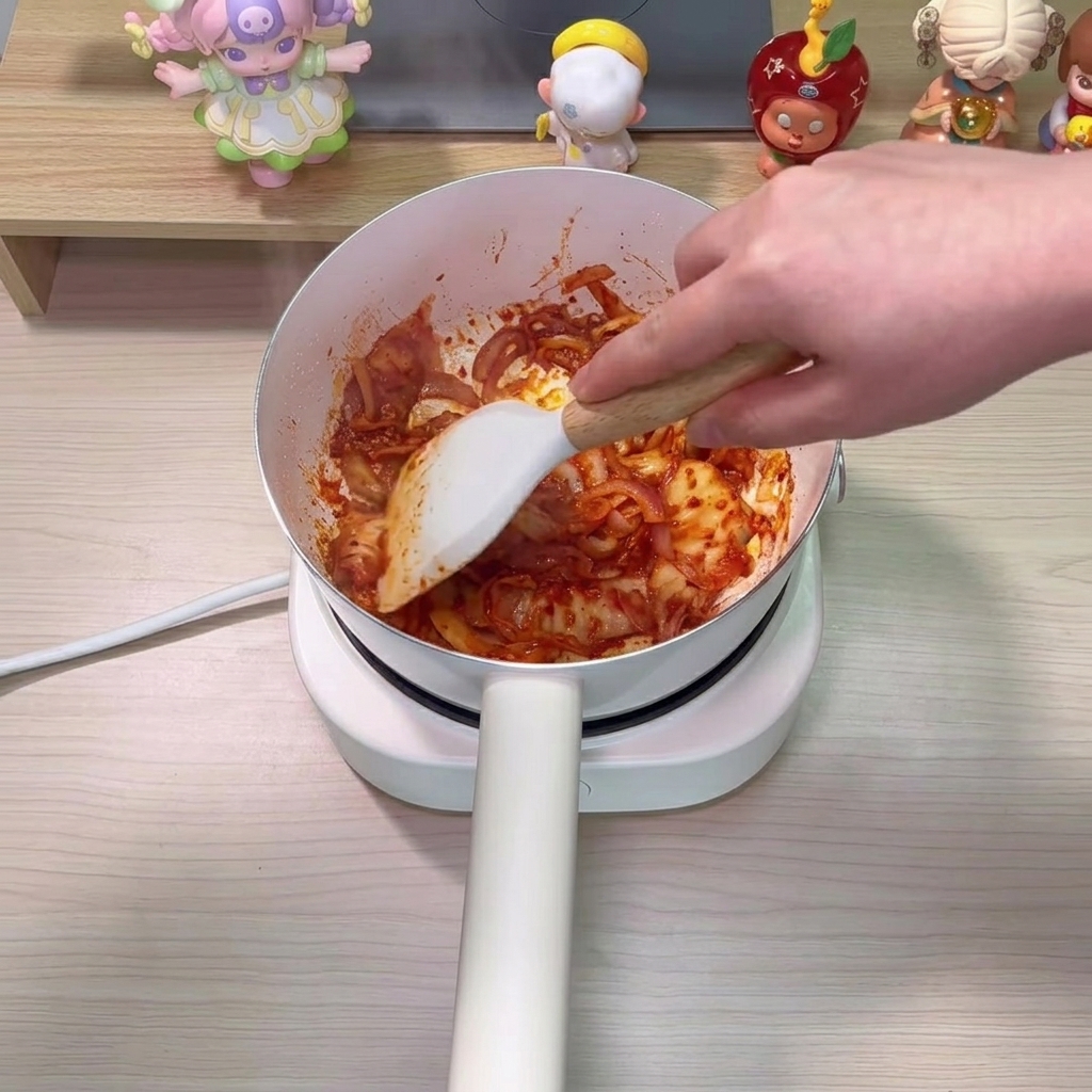 볶은 김치와 양파 위에 깨끗한 물을 붓는 모습.