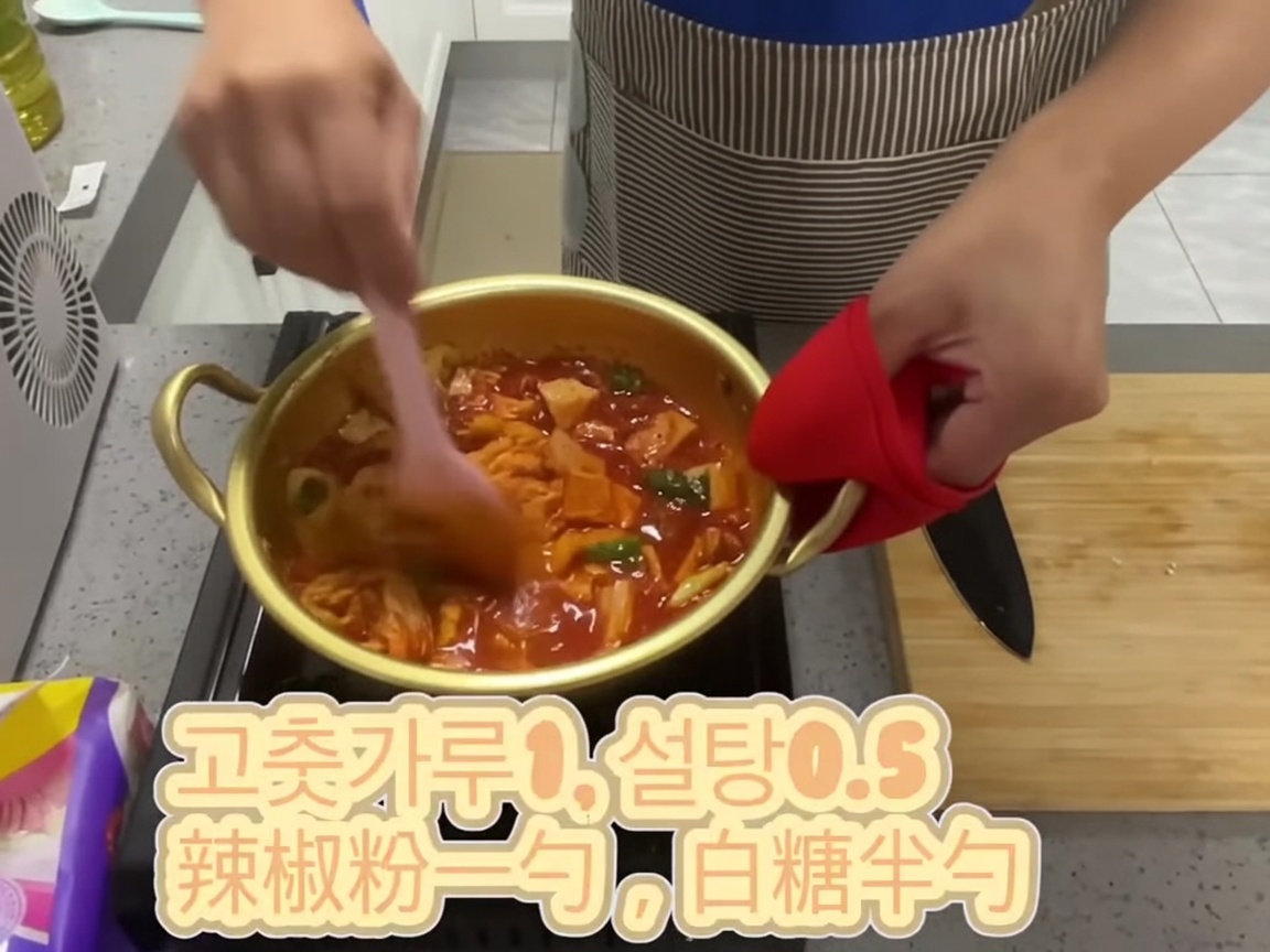 분홍색 주걱으로 양념 된 김치 혼합물을 골고루 섞는 모습.