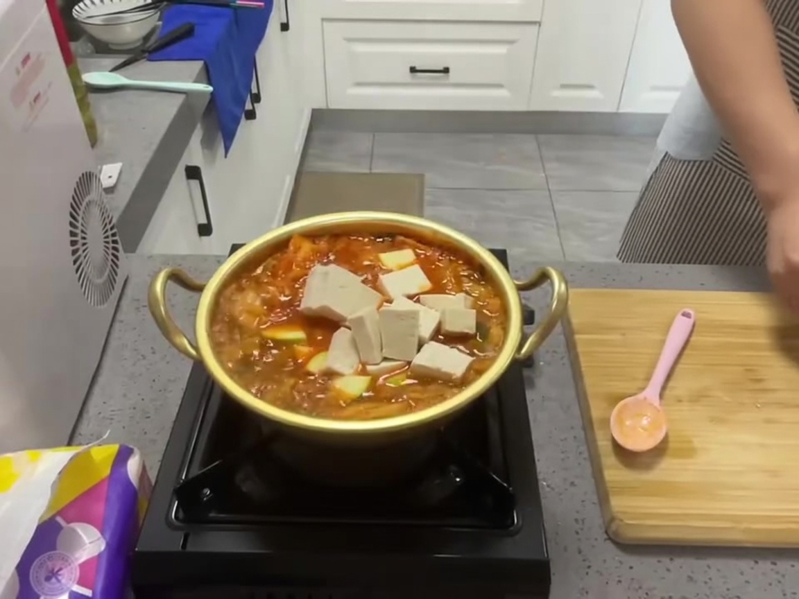 뜨겁게 끓어오르는 참치 김치찌개에 깍둑썰기 한 두부를 넣는 모습.