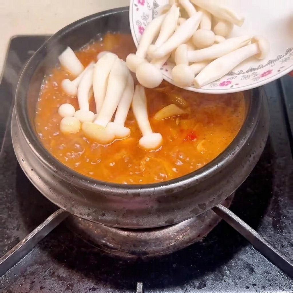 끓는 찌개에 해물버섯을 넣는 모습.