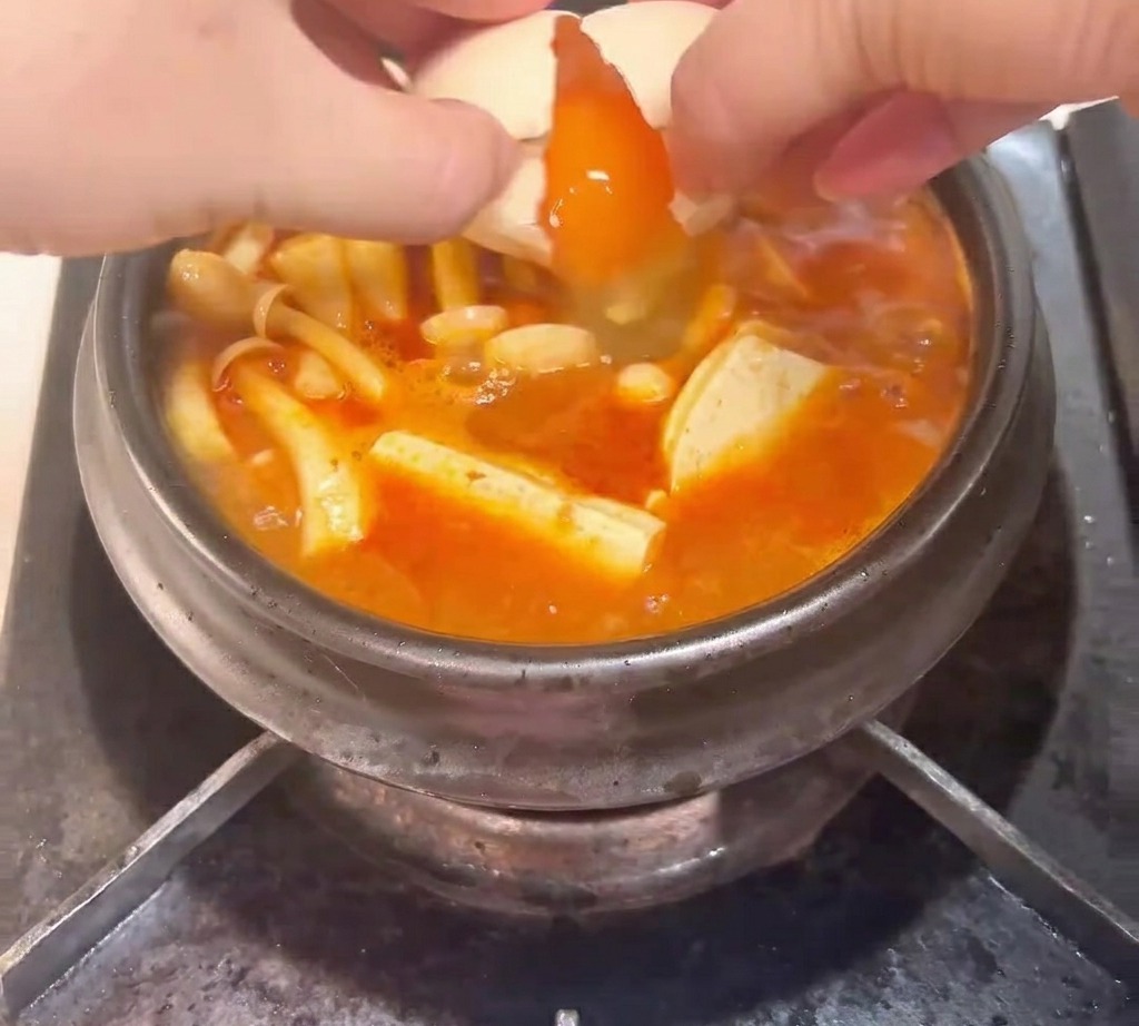 찌개 위에 달걀을 깨 넣는 모습.