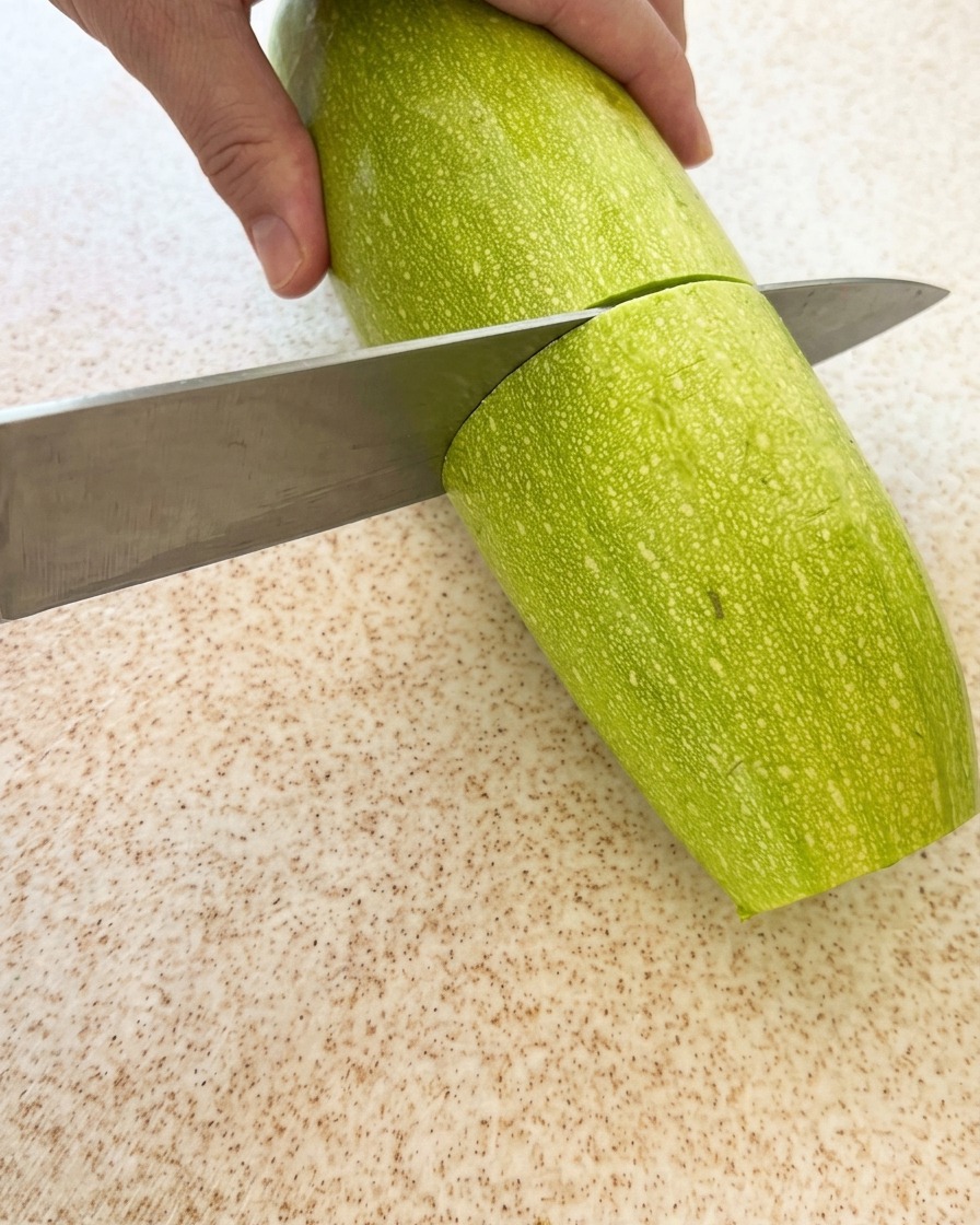 신선한 애호박을 도마 위에서 적당한 크기로 써는 모습.
