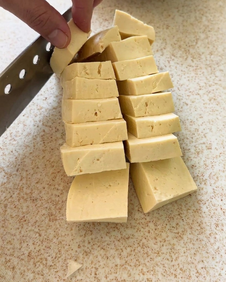 도마 위에서 단단한 두부를 일정한 큐브 모양으로 자르는 모습.