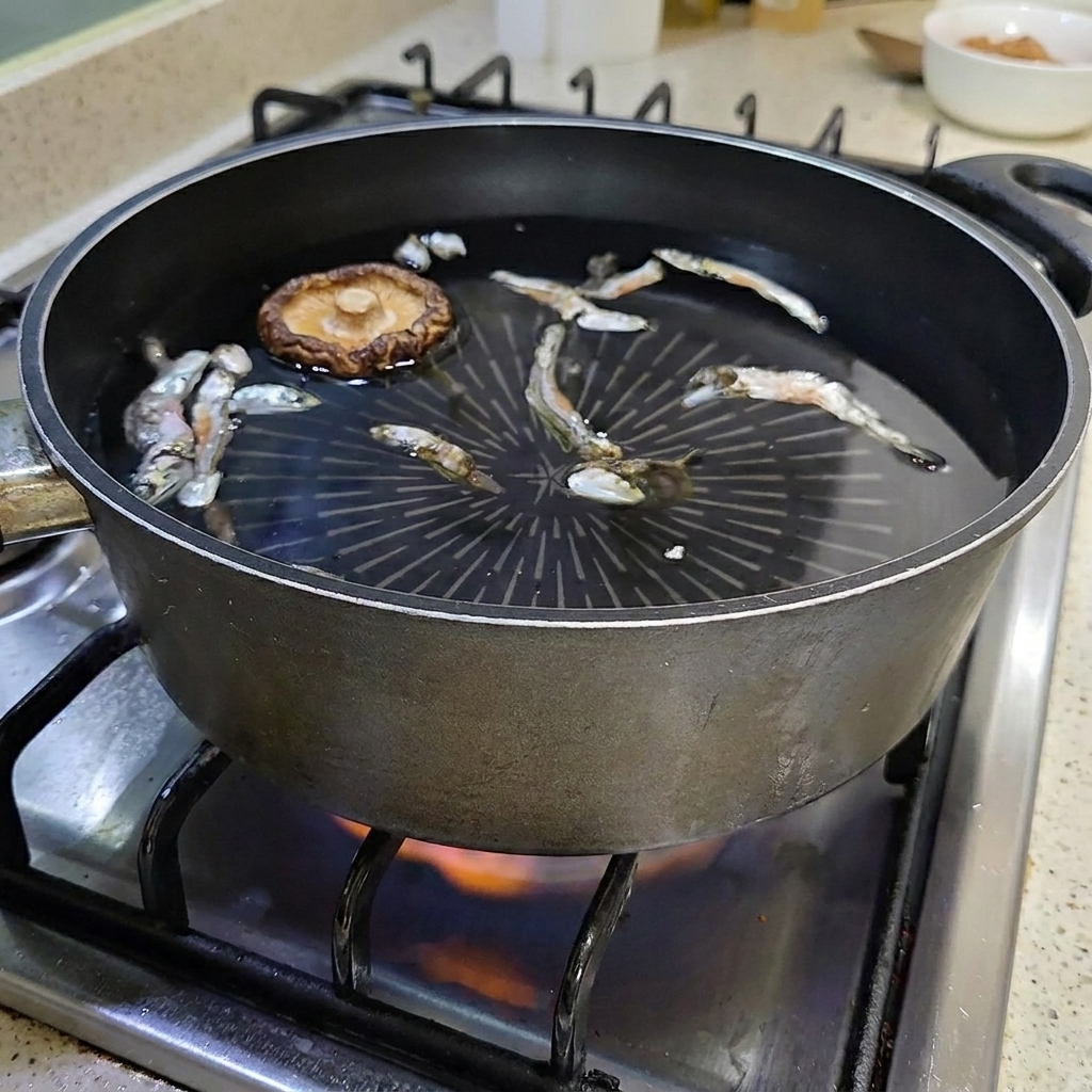 물과 멸치가 담긴 냄비에 말린 표고버섯을 넣는 모습