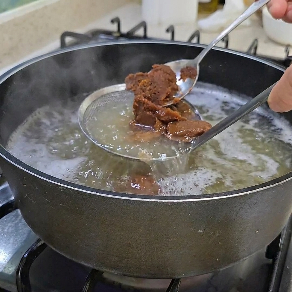 맑은 육수에 된장을 풀어 넣는 모습