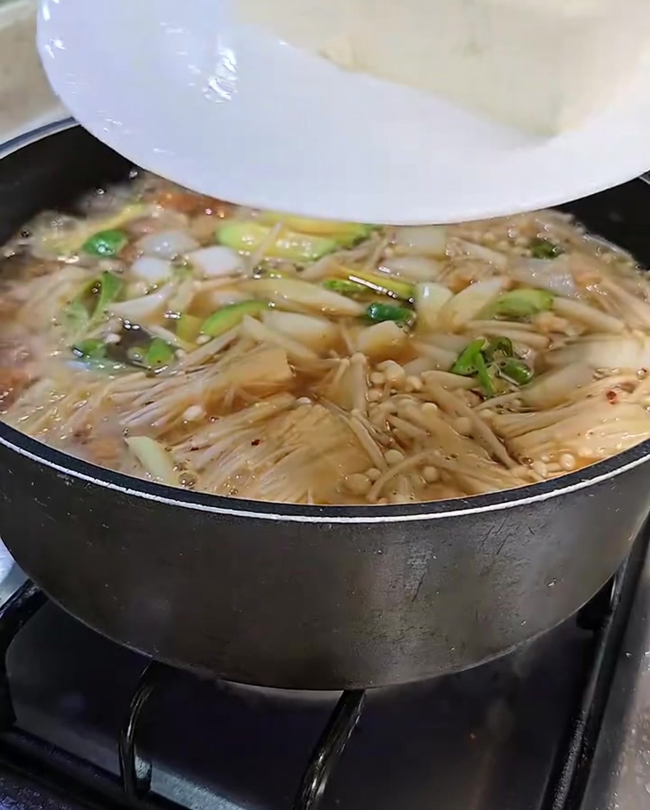 썰어둔 두부를 찌개에 조심스럽게 넣는 모습
