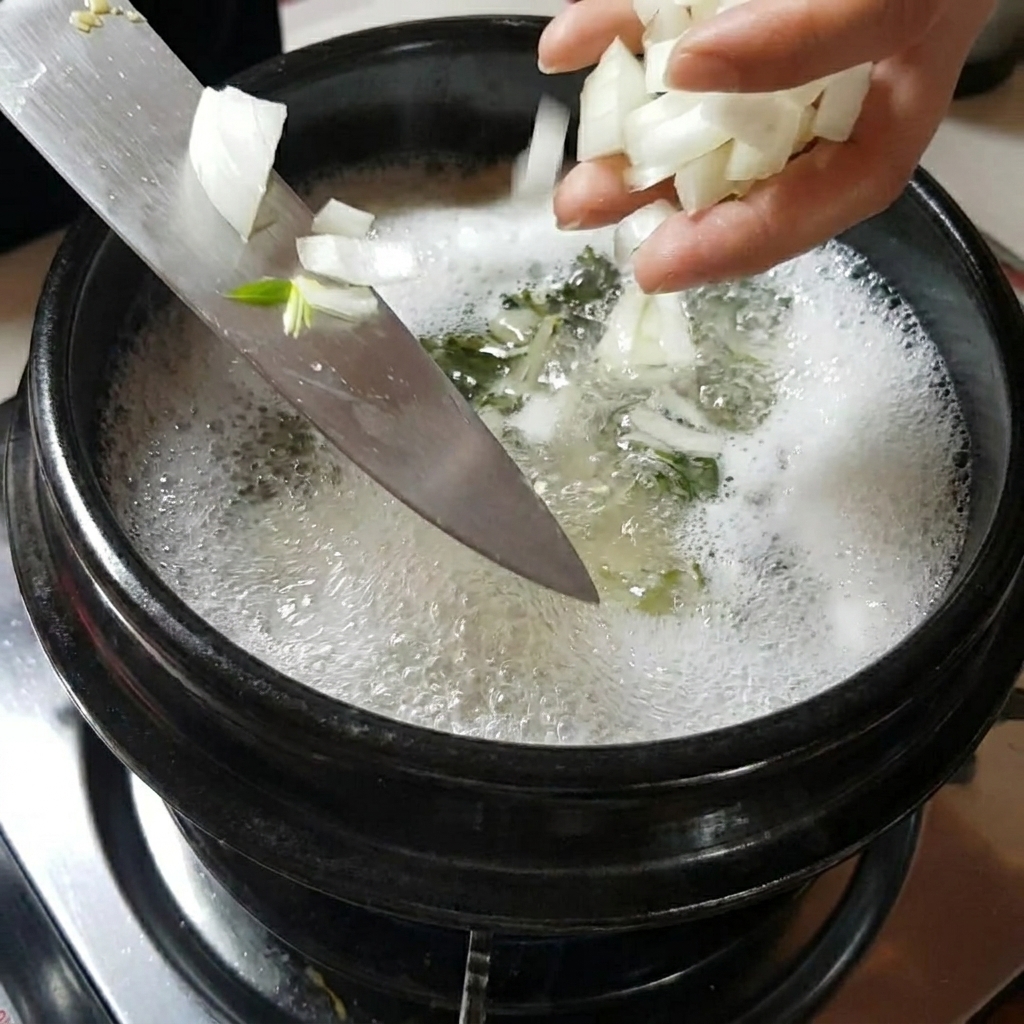 끓고 있는 찌개 냄비에 채 썬 양파와 버섯을 넣는 손.