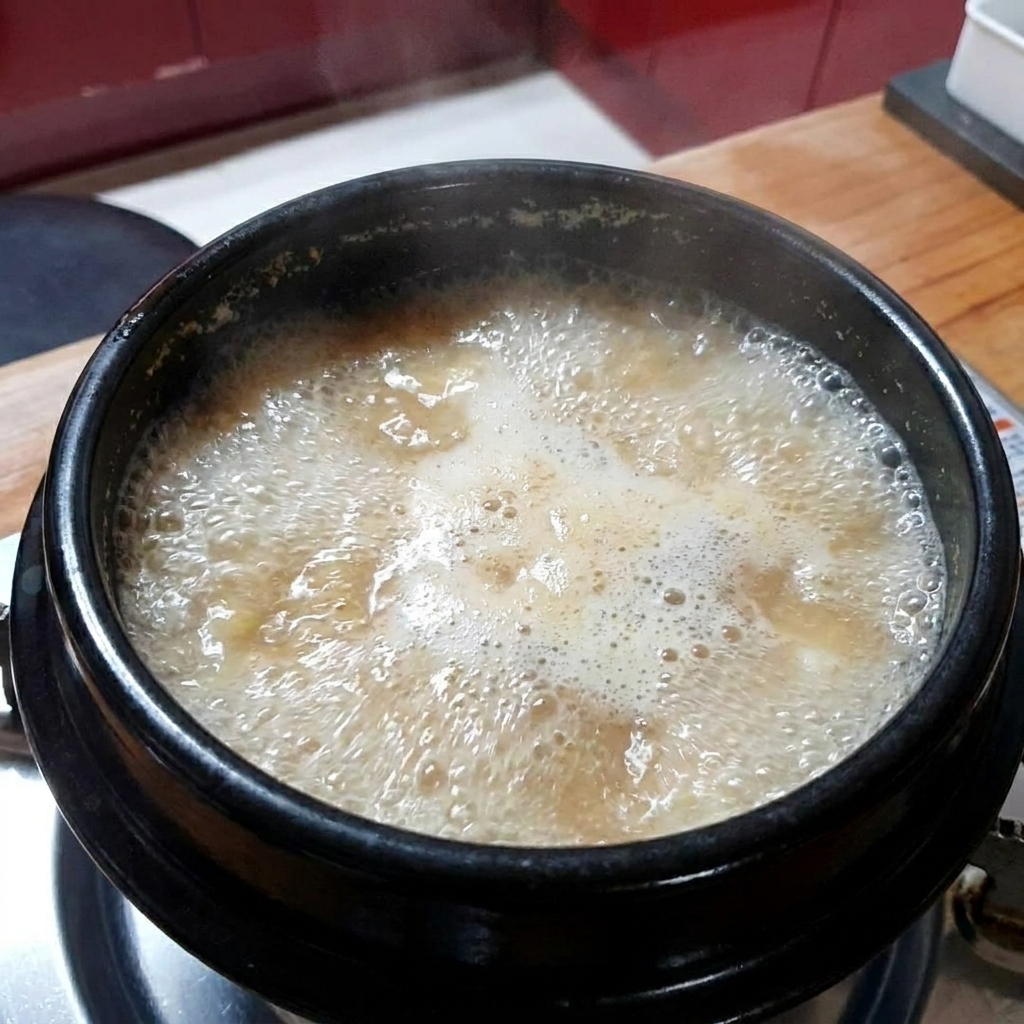 끓고 있는 된장찌개에 다진 마늘을 넣는 모습.