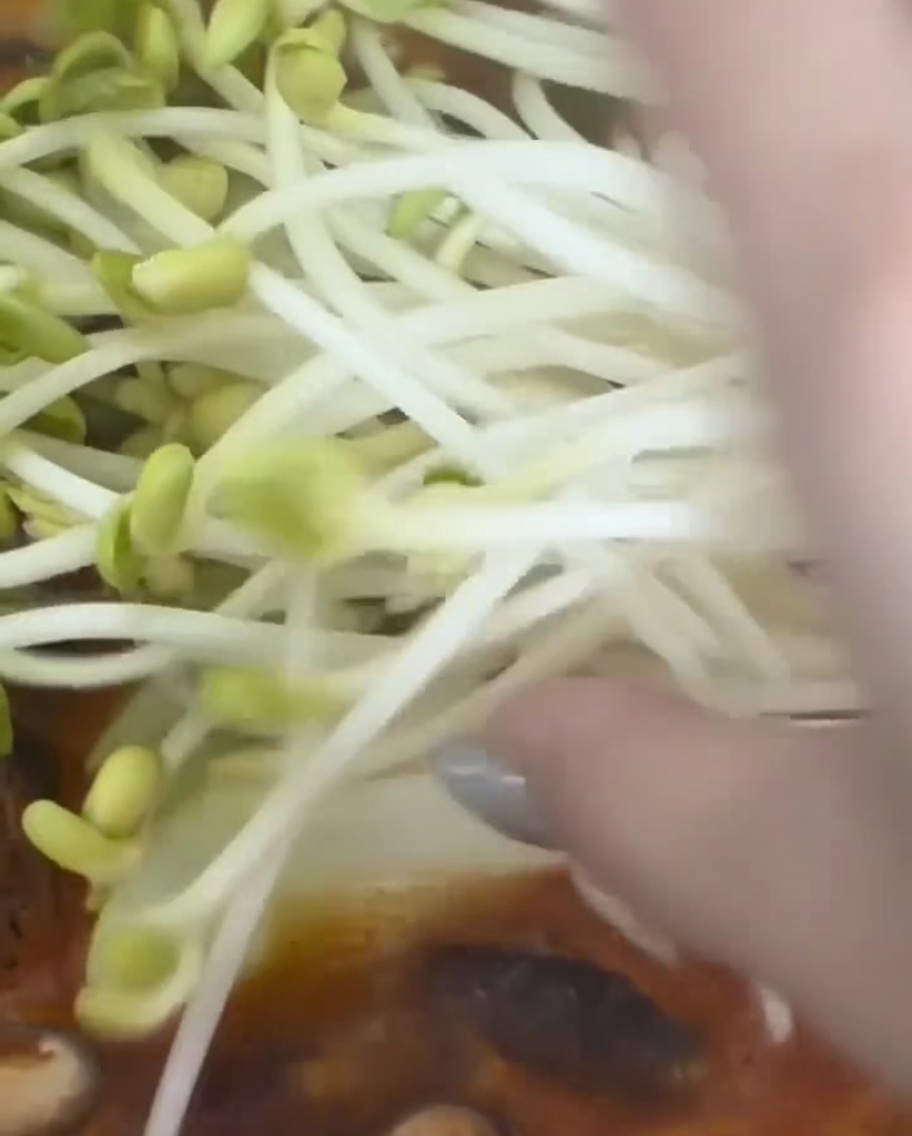 끓는 찌개에 콩나물을 한 줌 넣는 모습.