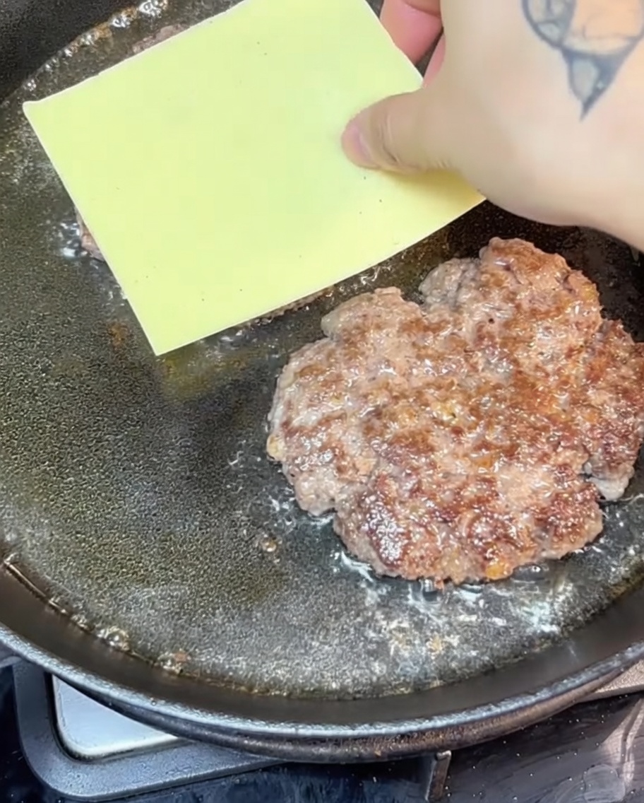 팬 위에서 패티 위에 올려진 치즈가 녹아내리는 모습.