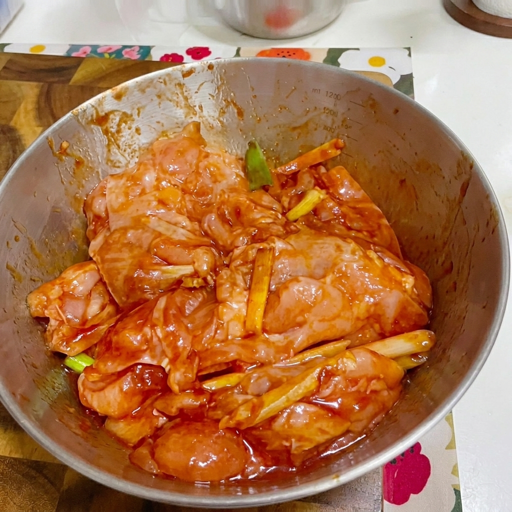 플라스틱 랩으로 덮인 양념된 치킨이 담긴 볼.