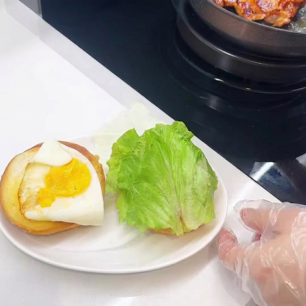 토스트한 번 위에 치킨, 치즈, 계란후라이, 상추를 쌓아 올리는 모습.