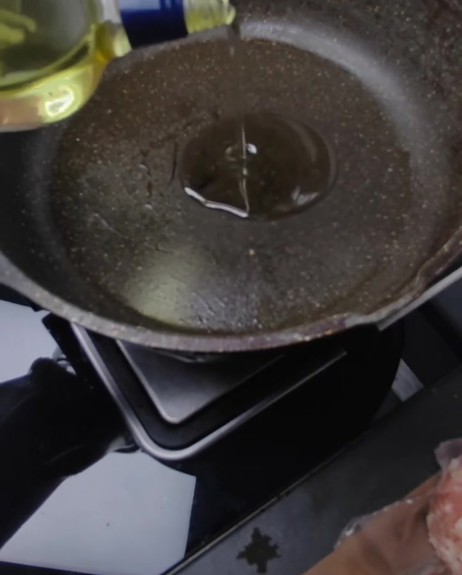 올리브유와 버터를 두른 팬에서 돼지고기 패티를 굽는 모습.