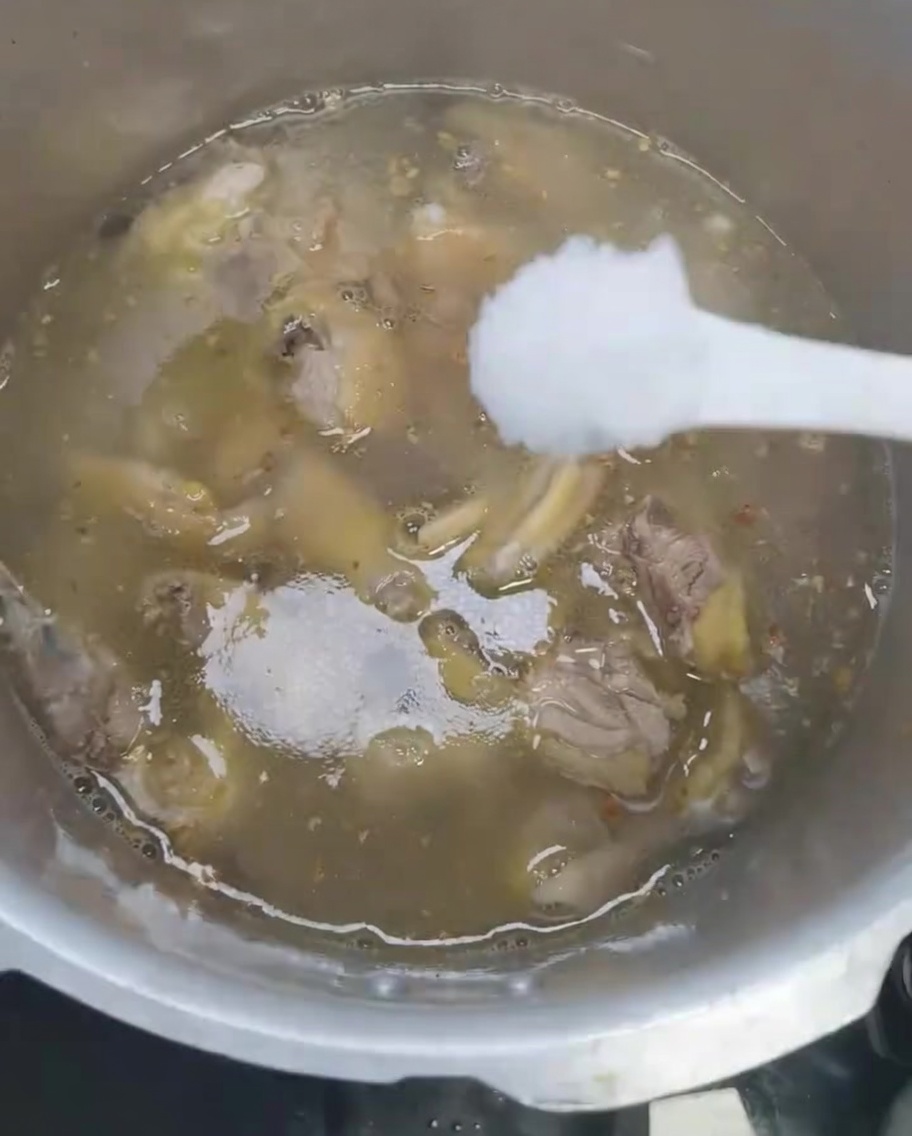 압력솥 안의 닭고기 수프에 소금을 넣는 모습.