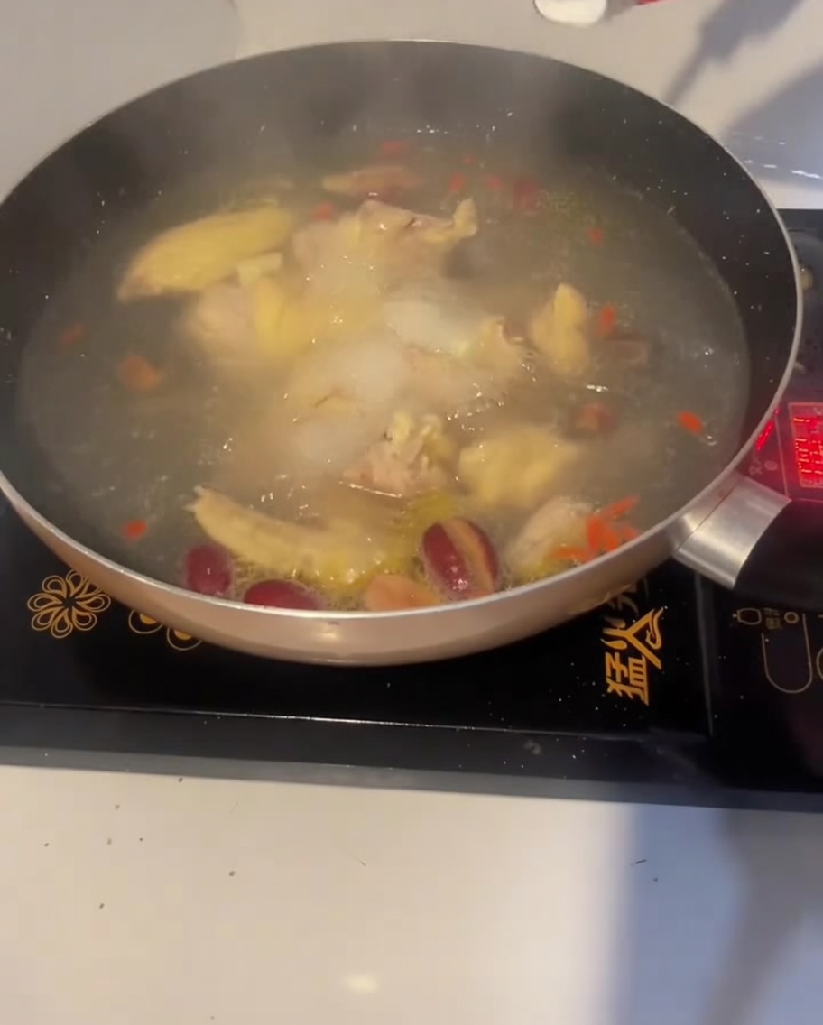 끓는 닭고기 수프에 소금 한 숟가락을 넣어 간을 맞추는 모습.