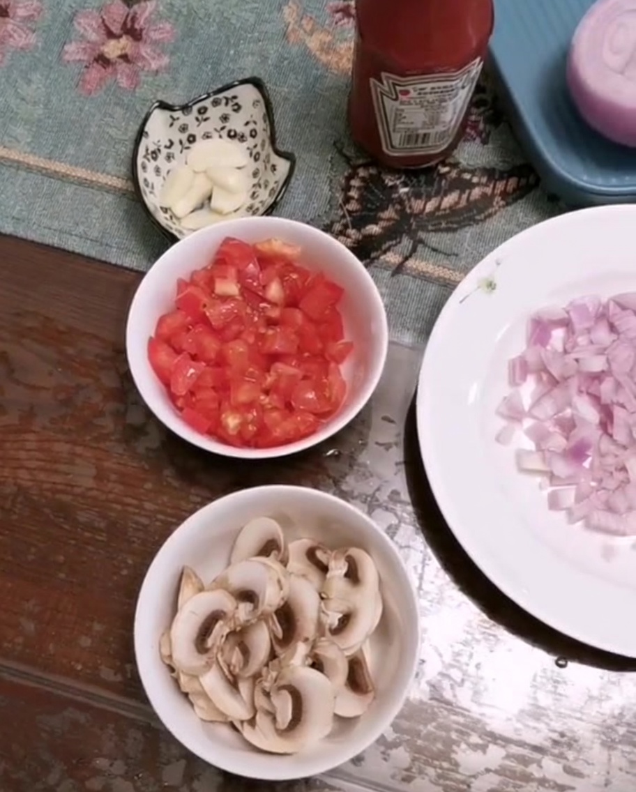 도마 위에 놓인 잘게 썬 토마토, 슬라이스한 버섯, 다진 마늘.