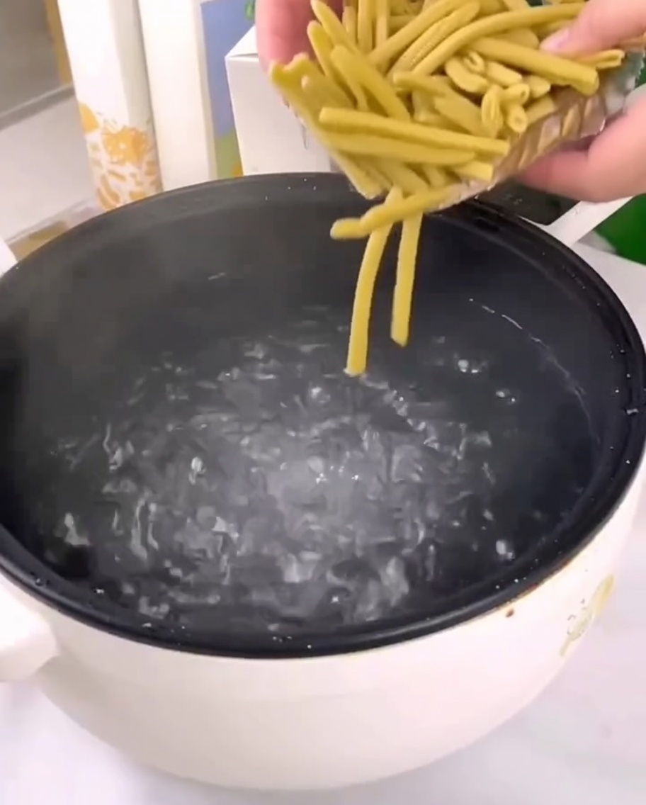 끓는 물이 담긴 냄비에 건조된 기장 펜네 파스타를 붓는 모습.