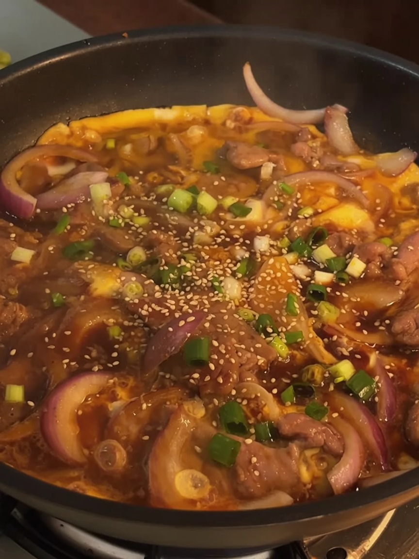 완성된 소고기 덮밥 재료 위로 대파와 깨를 뿌려 마무리한 모습.