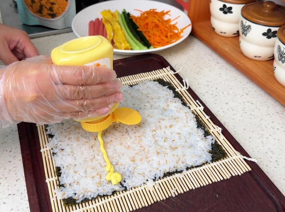 김밥 재료 위로 샐러드 드레싱을 뿌려 마무리 준비를 하는 모습.