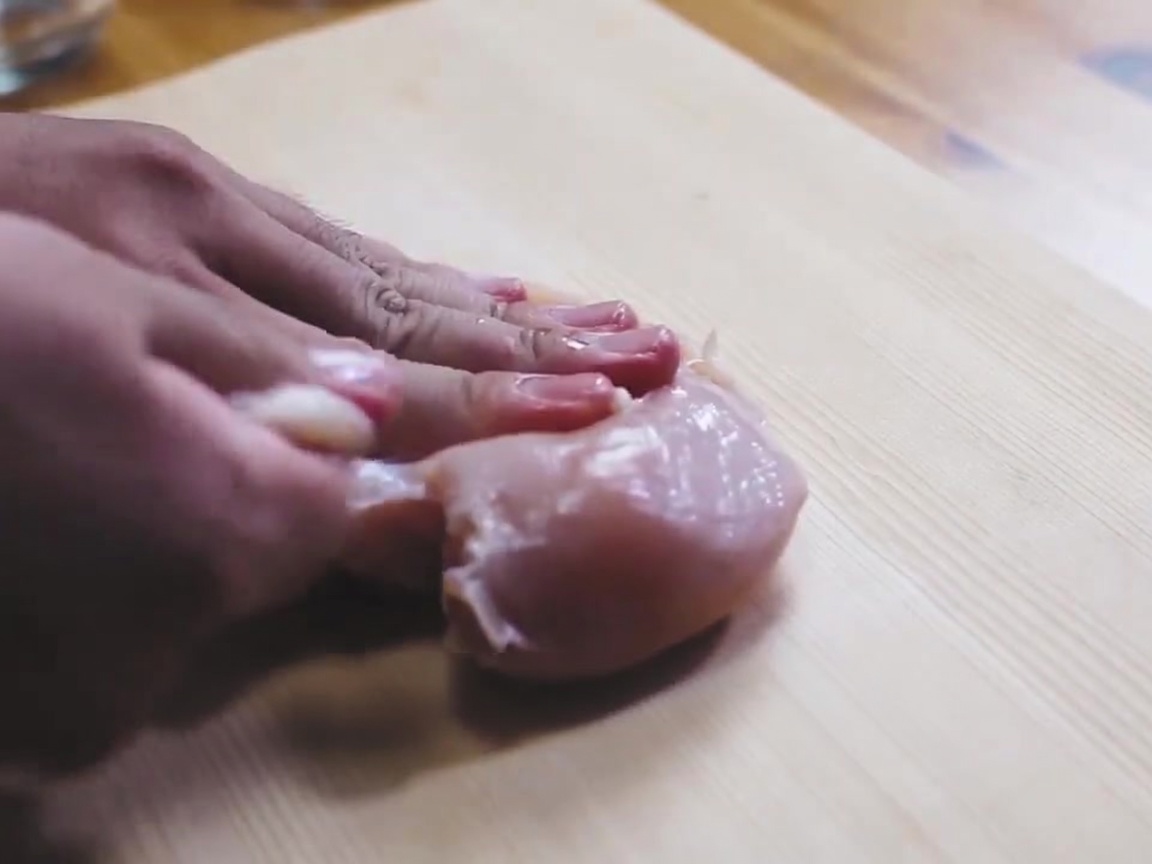 도마 위에서 닭가슴살 양면에 소금을 뿌리는 모습.