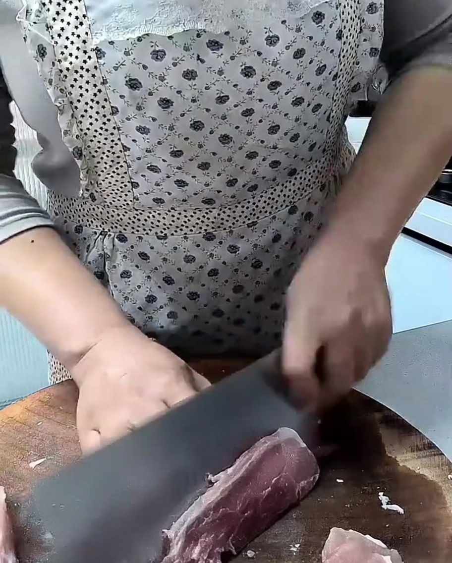 도마 위에서 생 돼지고기 등심을 칼로 썰고 있는 모습.