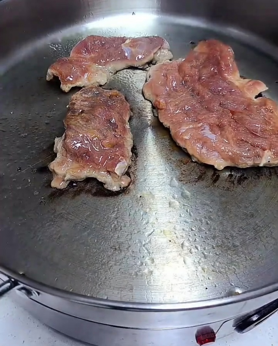 달궈진 팬에 돼지고기를 올려 노릇하게 굽는 모습.