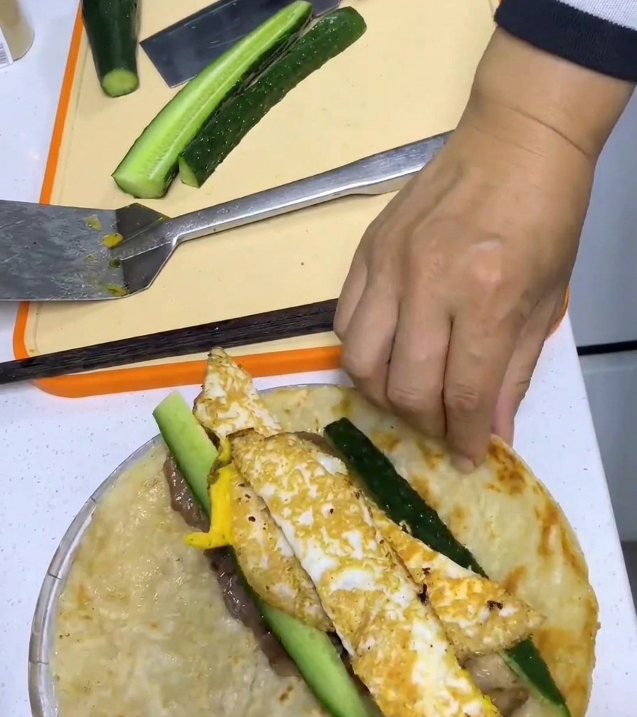 파전을 재료와 함께 단단하게 말아 완성하는 모습.