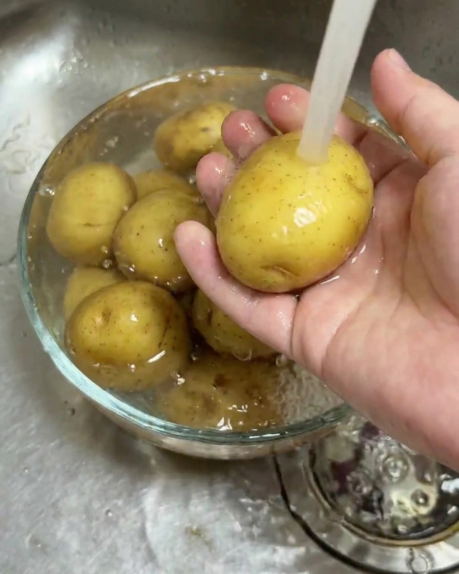 유리 볼에 담긴 알감자를 흐르는 물에 깨끗이 씻는 모습.