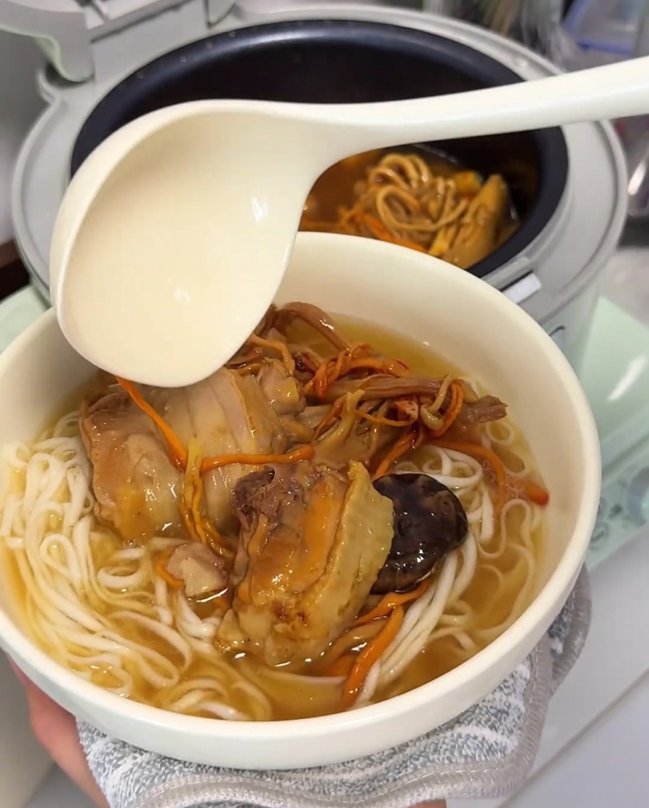 잘 익은 국수 위로 뜨거운 닭고기 버섯 육수를 붓는 모습.