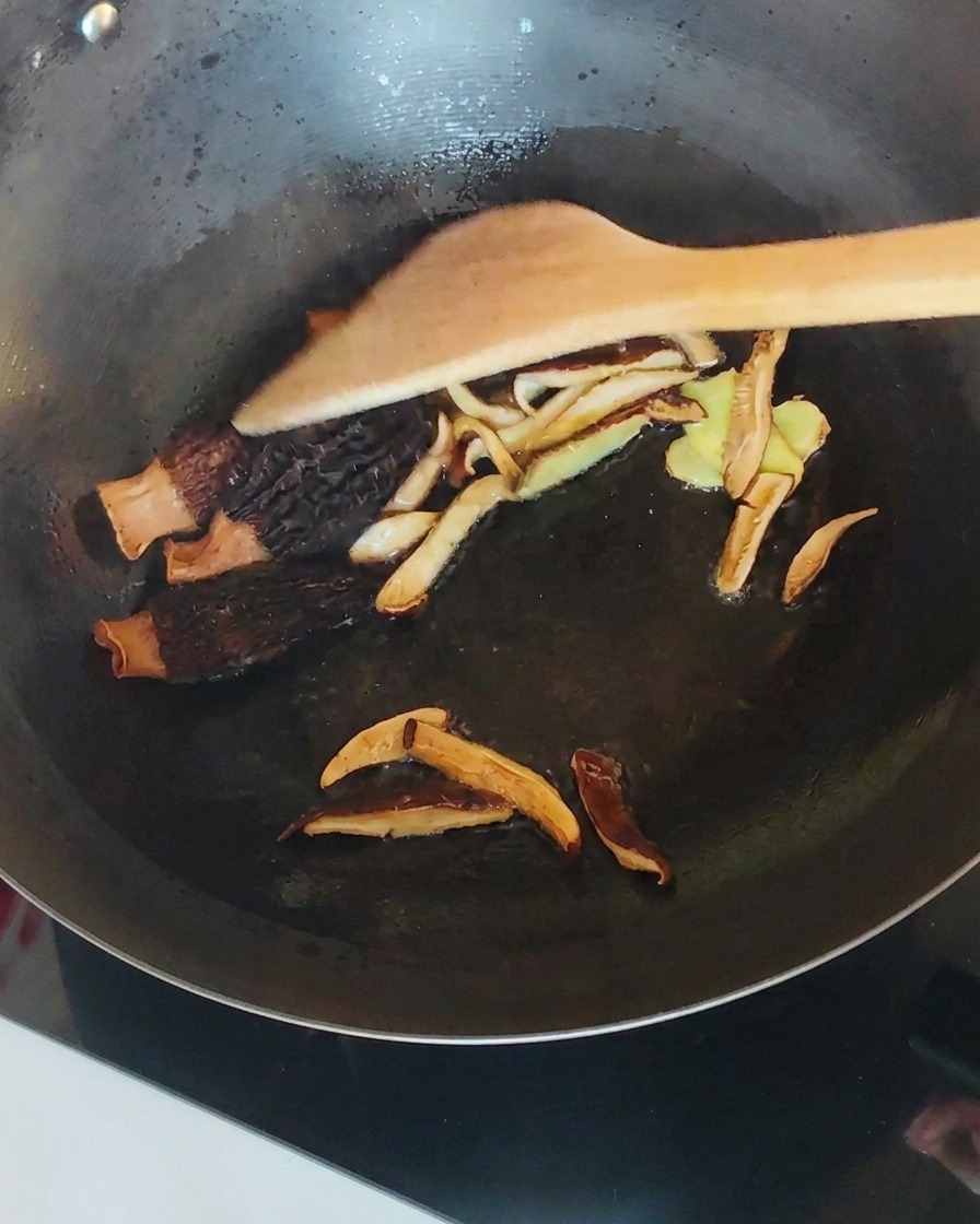 볶은 버섯과 생강이 담긴 웍에 찢어둔 닭고기를 넣고 섞는 모습.